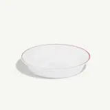 A white shallow bowl with a thin red rim sits on a plain background.
