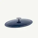 A glossy, dark blue oval-shaped lid with a central metal handle is depicted against a white background.