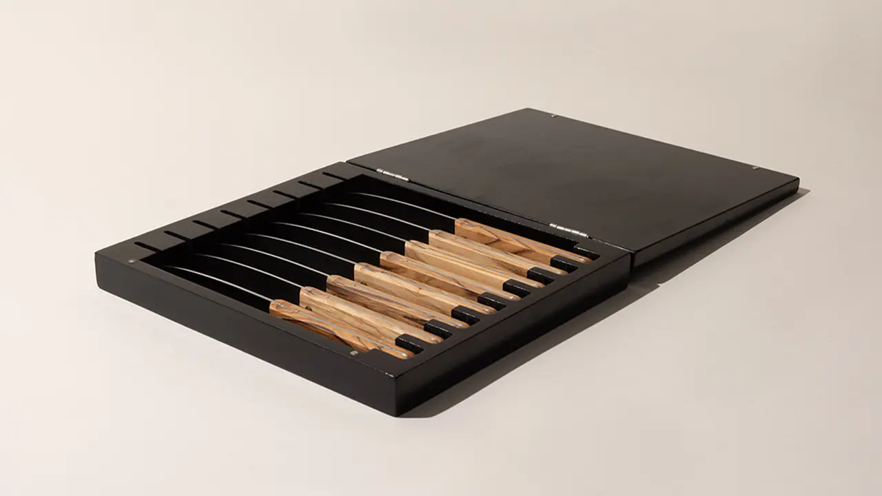 A sleek, open black box displaying a set of chopsticks arranged in parallel on a light background.
