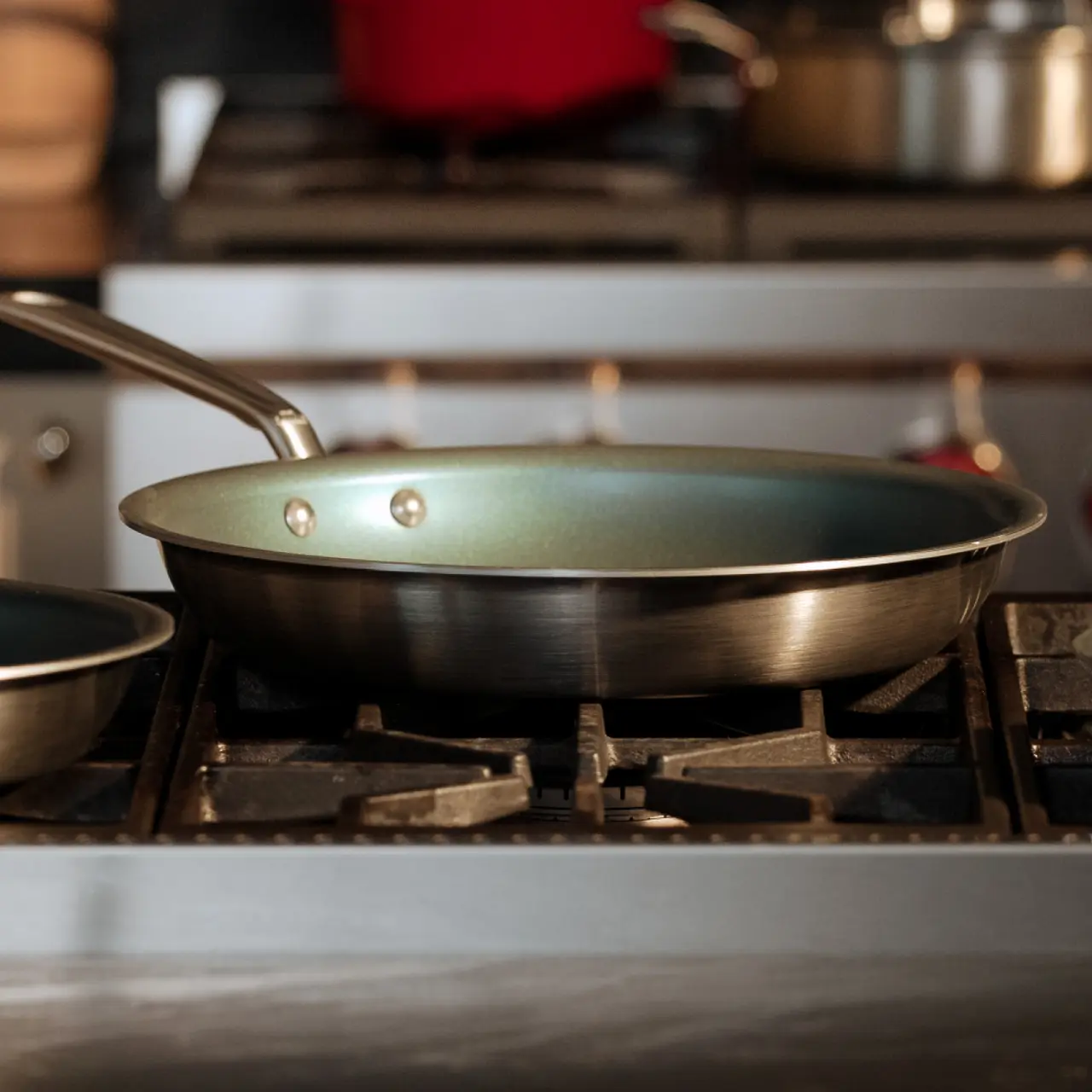 A frying pan sits on a gas stove-top, ready for cooking.