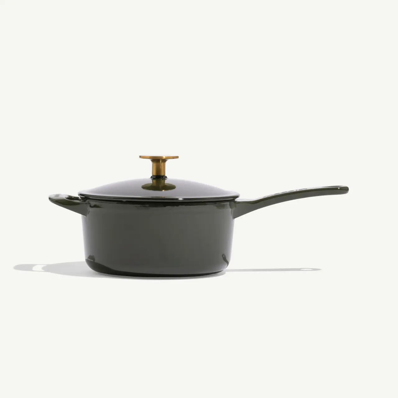 A dark green cooking pot with a matching lid and a golden handle stands on a light background.