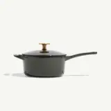 A dark green cooking pot with a matching lid and a golden handle stands on a light background.
