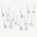 A collection of transparent glass tumblers arranged in a staggered formation against a light background.