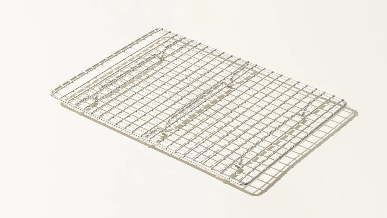 A stainless steel cooling rack is placed against a plain, light background.