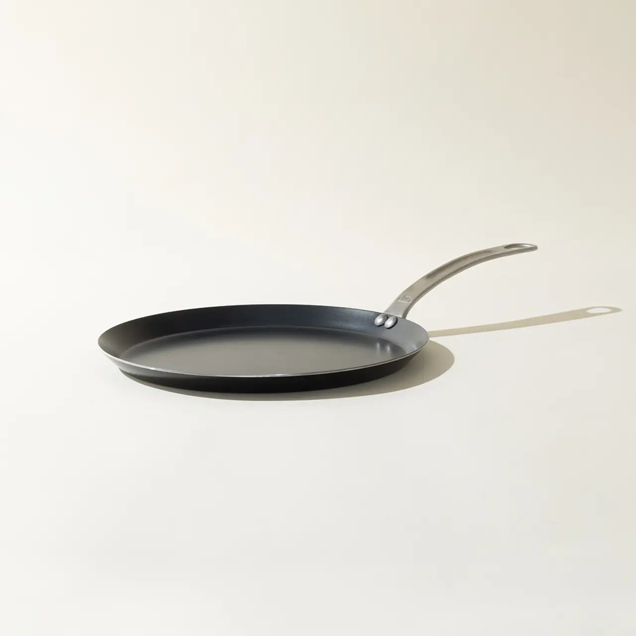 A black non-stick frying pan with a silver handle on a plain background.