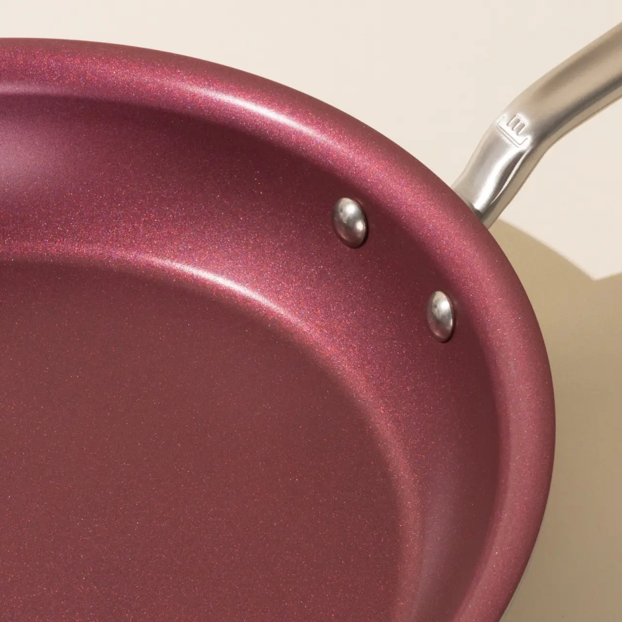Close-up of a maroon non-stick frying pan with a silver handle.