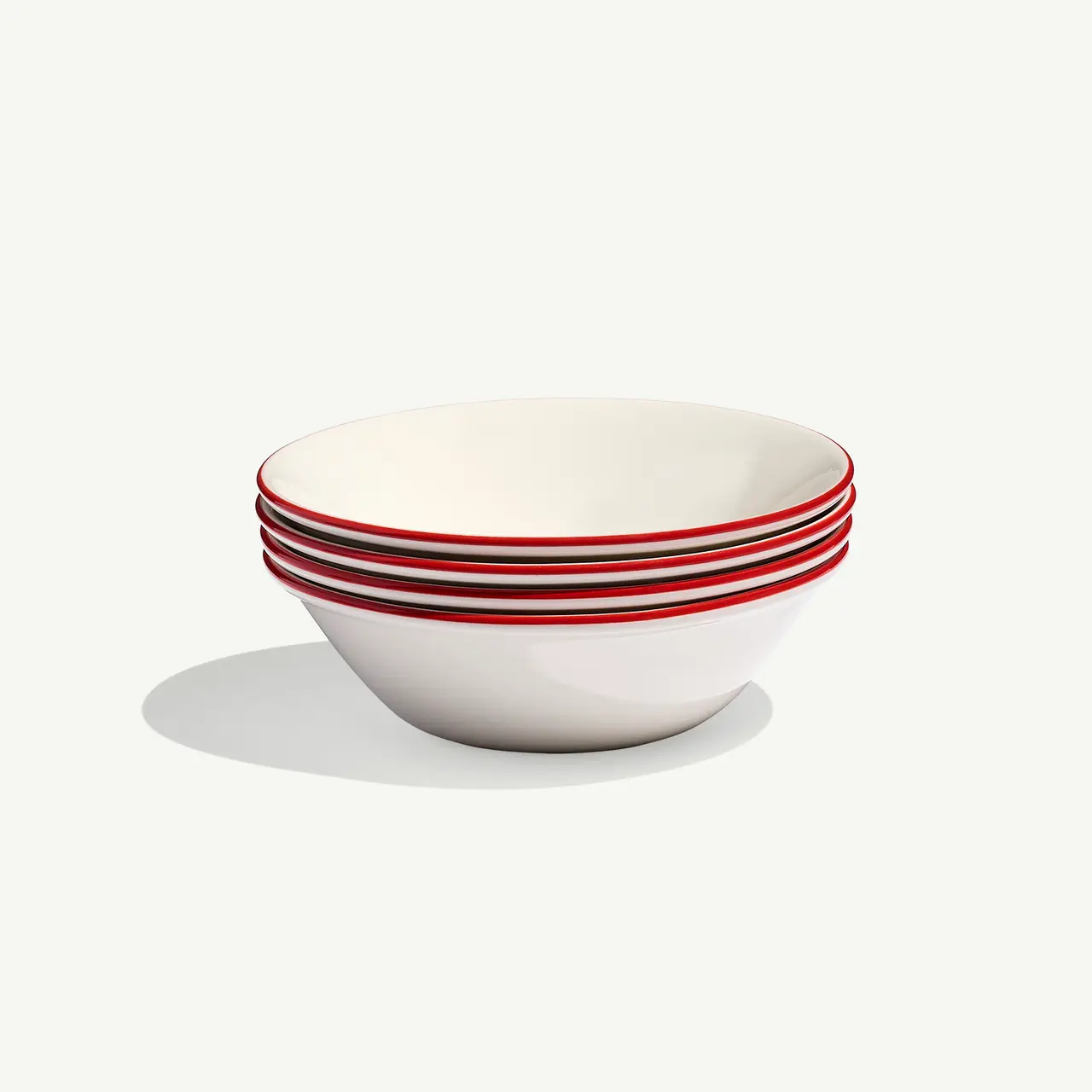 A stack of six white bowls with red rims is placed against a plain background.