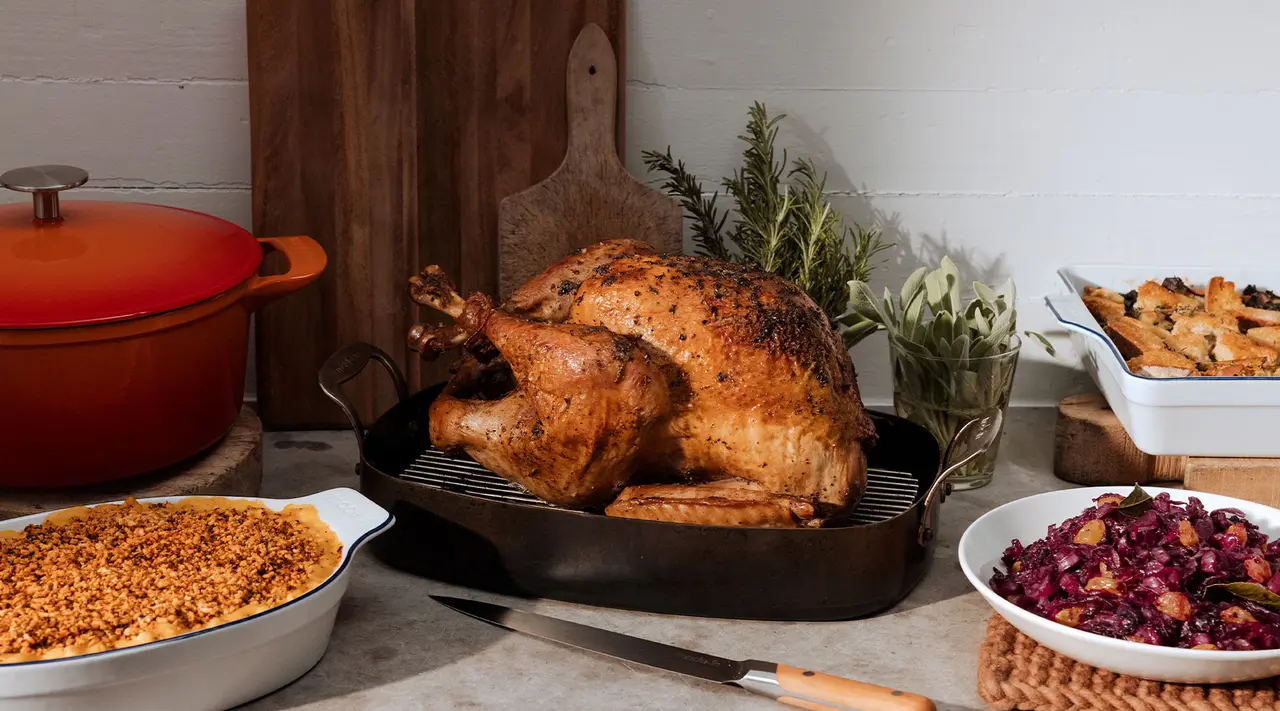 A roasted turkey on a platter surrounded by various side dishes on a table, suggesting a festive or holiday meal setting.