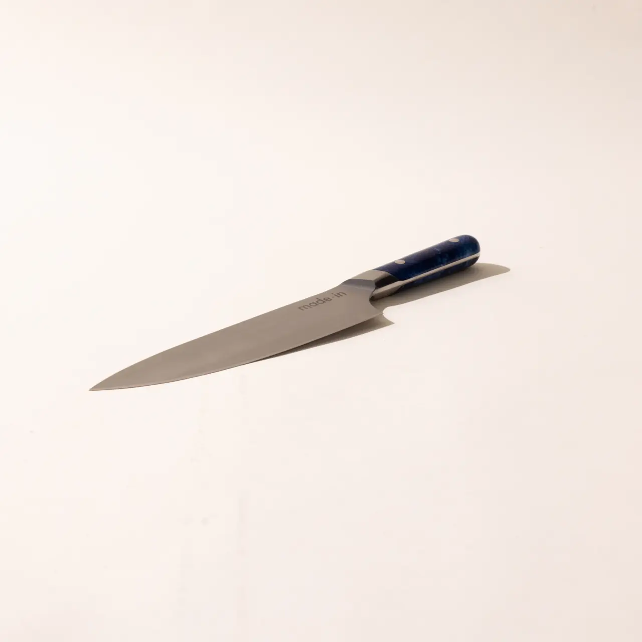 A kitchen knife with a blue handle lying on a plain white surface.