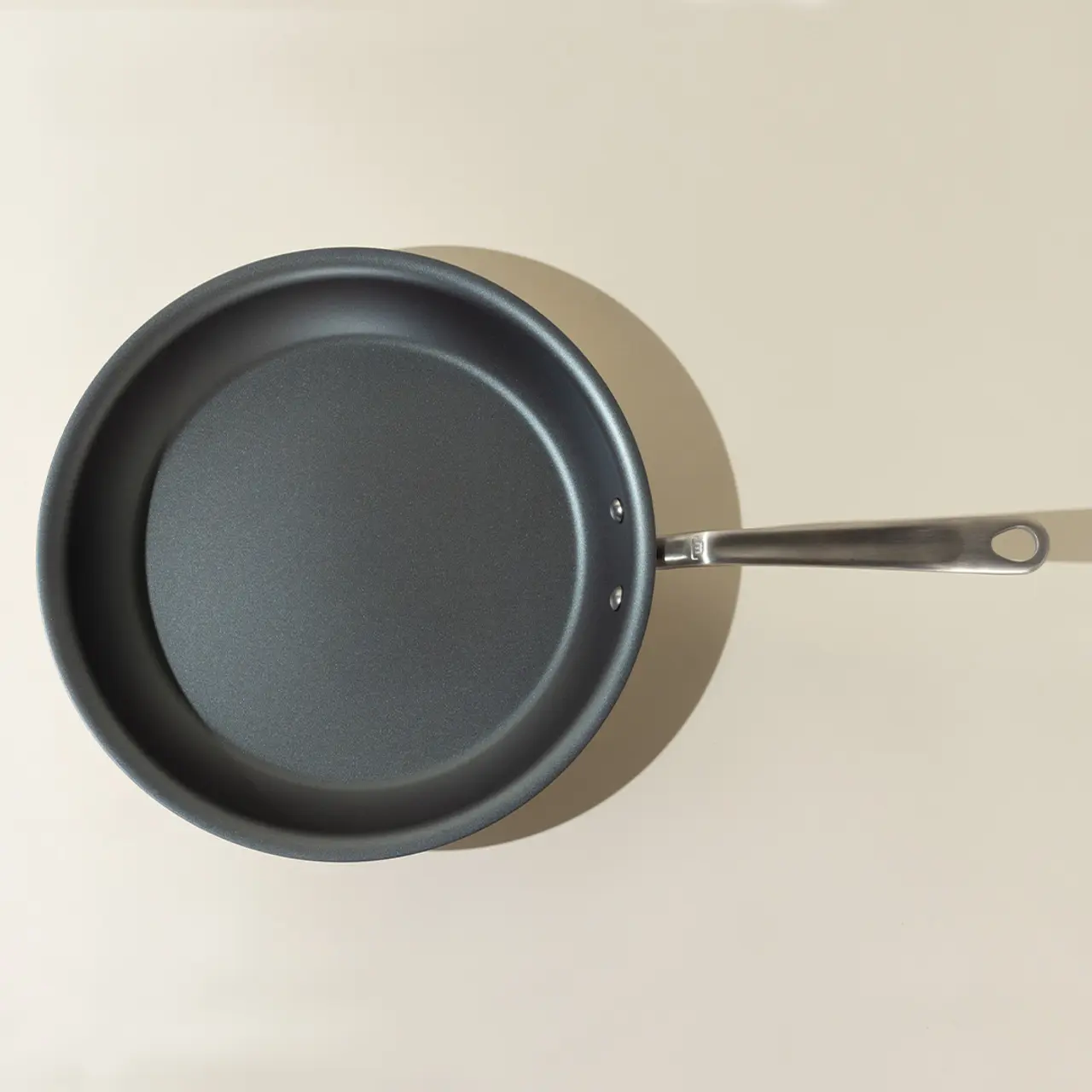 A non-stick frying pan with a stainless steel handle is viewed from above.