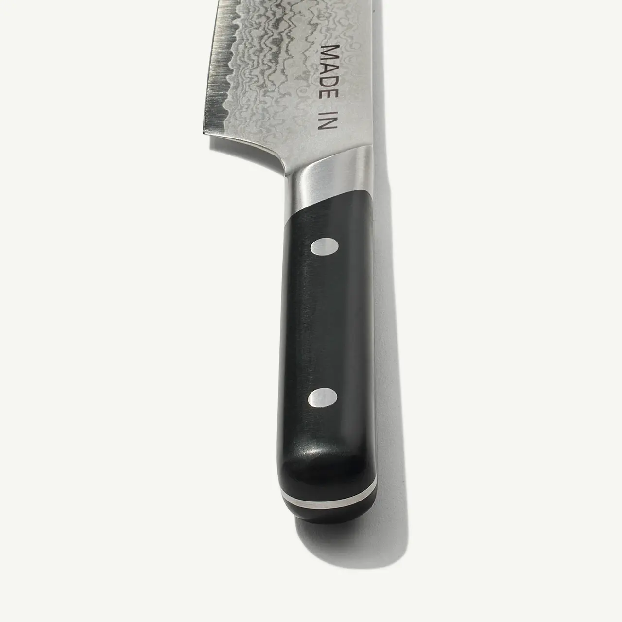 A chef's knife with a black handle and a stainless steel blade featuring the text "MADE IN."