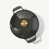 A round, dark green enameled cast iron pot with a brass knob on its lid.