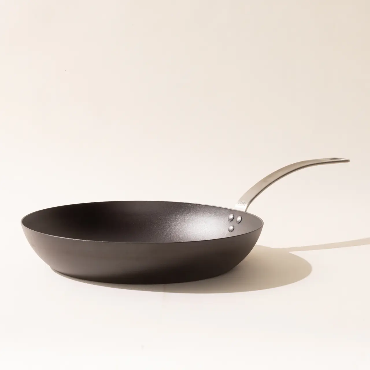 A black non-stick frying pan with a stainless steel handle shown against a light background.