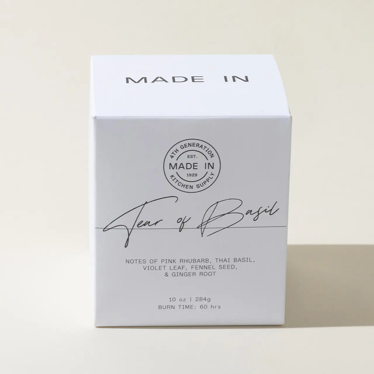 A white candle box with the words "MADE IN" at the top and "Terra of Basil" in cursive, along with a description of the candle's scent notes.