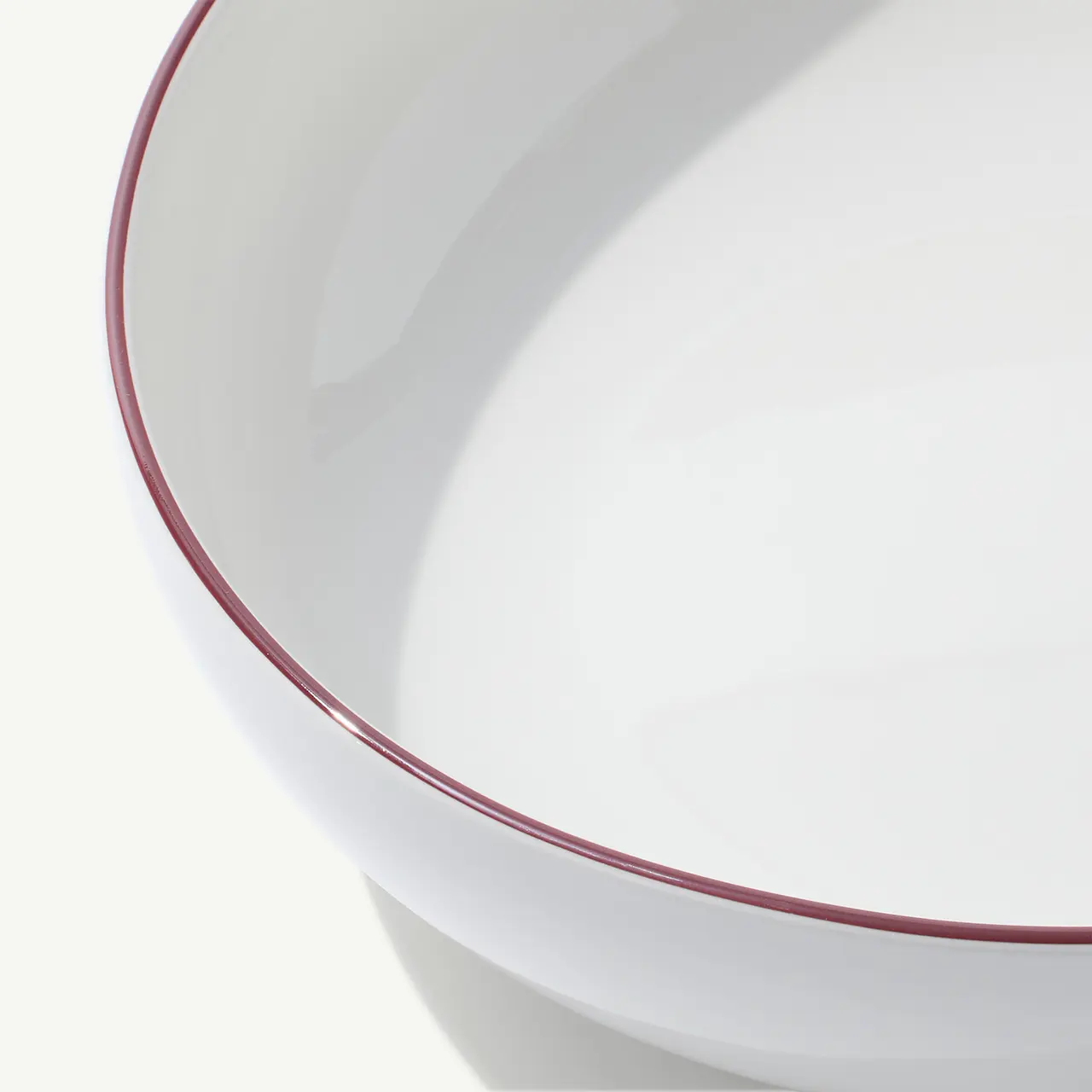 A white ceramic bowl with a thin red rim is shown against a plain background.