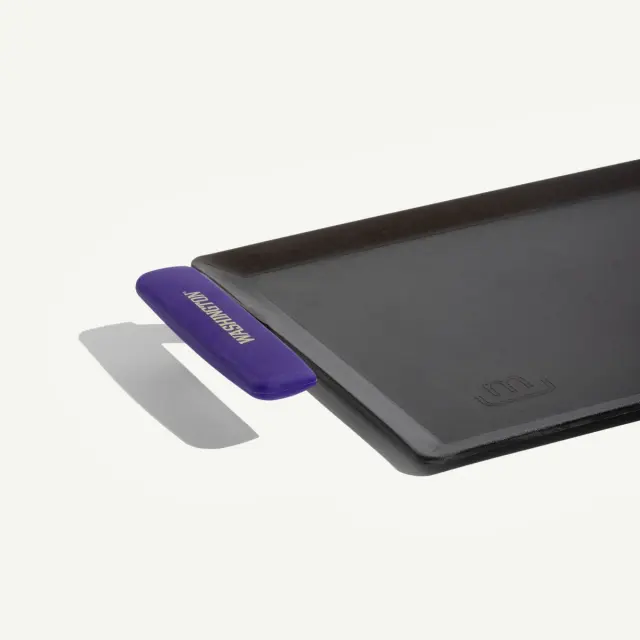 A black rectangular griddle with a purple handle on one side.