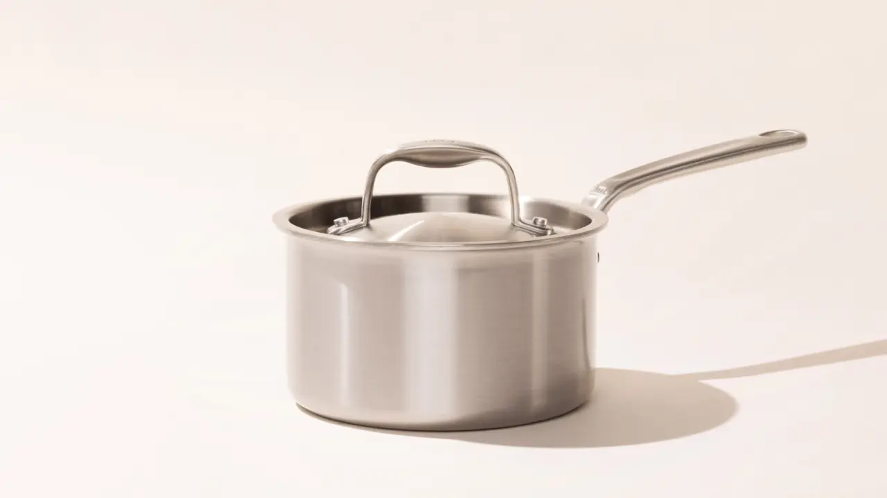 A stainless steel saucepan with a long handle on a light background.