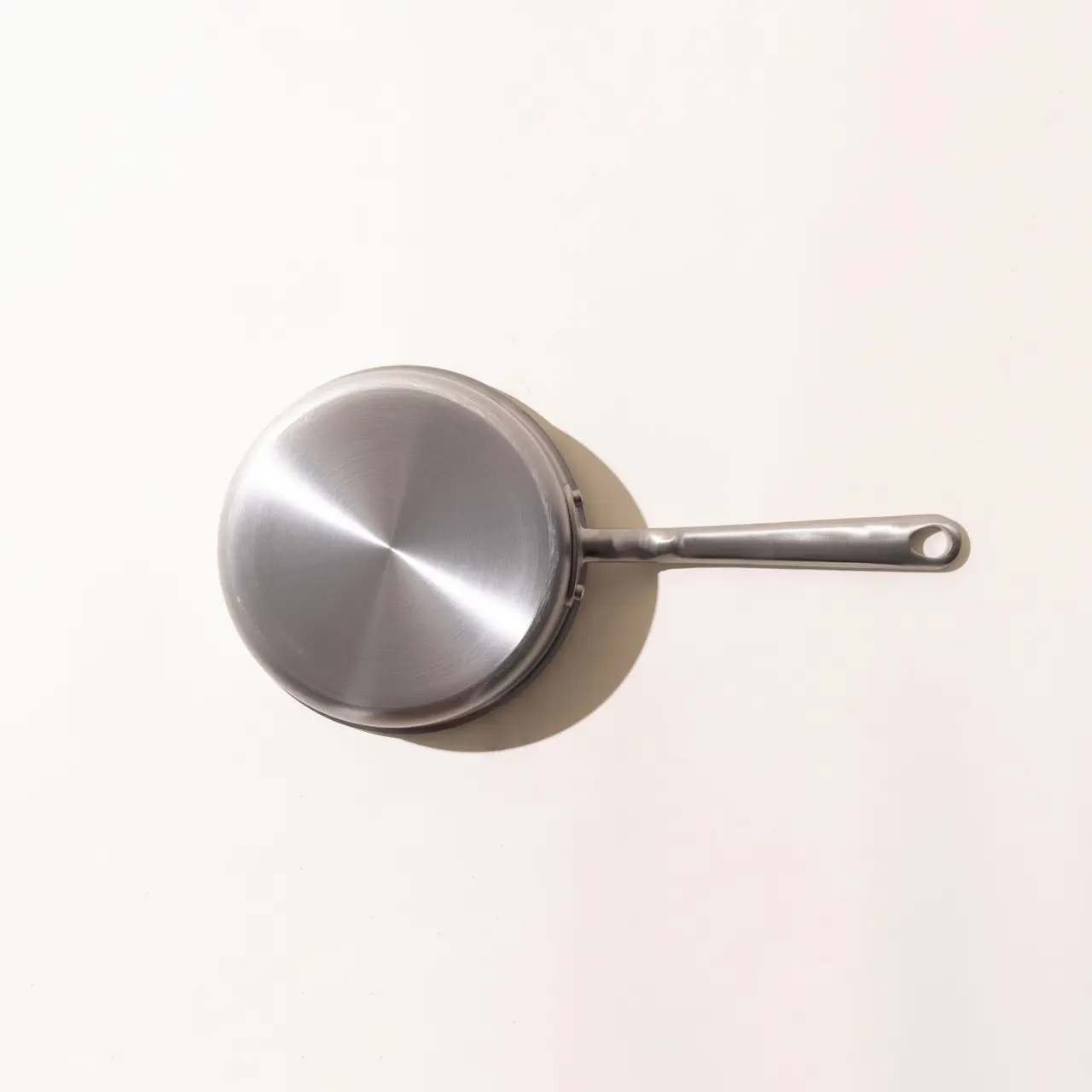 A stainless steel frying pan displayed against a light background.