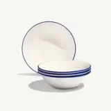 Four white bowls with blue rims are stacked in front of a matching plate.