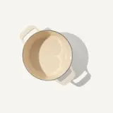 A beige mug is situated on a light surface, casting a soft shadow.