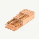 A wooden knife block holds three knives with wooden handles.