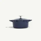 A navy blue cast iron Dutch oven with a lid and side handles is centered against a plain background.