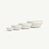 Four white ceramic bowls of varying sizes are arranged in a row from smallest to largest.