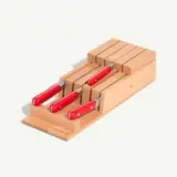 A wooden knife block holds five knives with red handles.