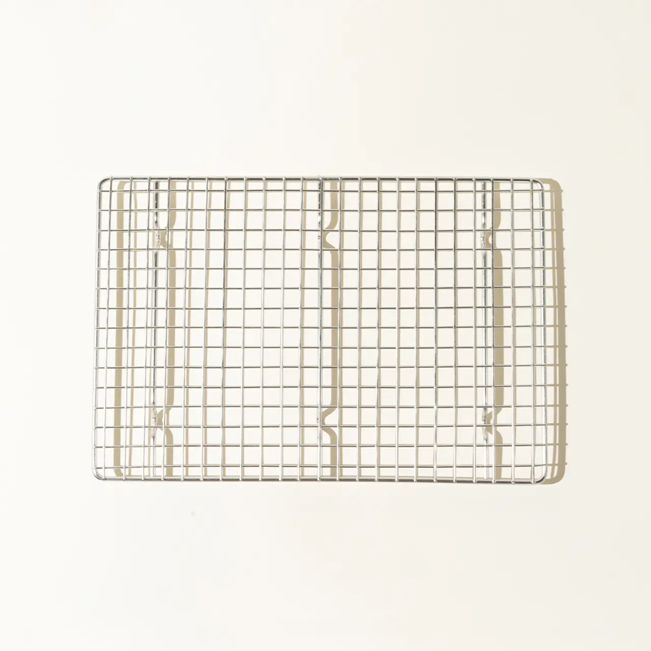 A simple metal cooling rack is centered on a plain, light background.