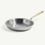 A stainless steel frying pan with a gold-colored handle is displayed against a light background.