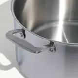 A stainless steel pot with a handle is shown from a top side angle.