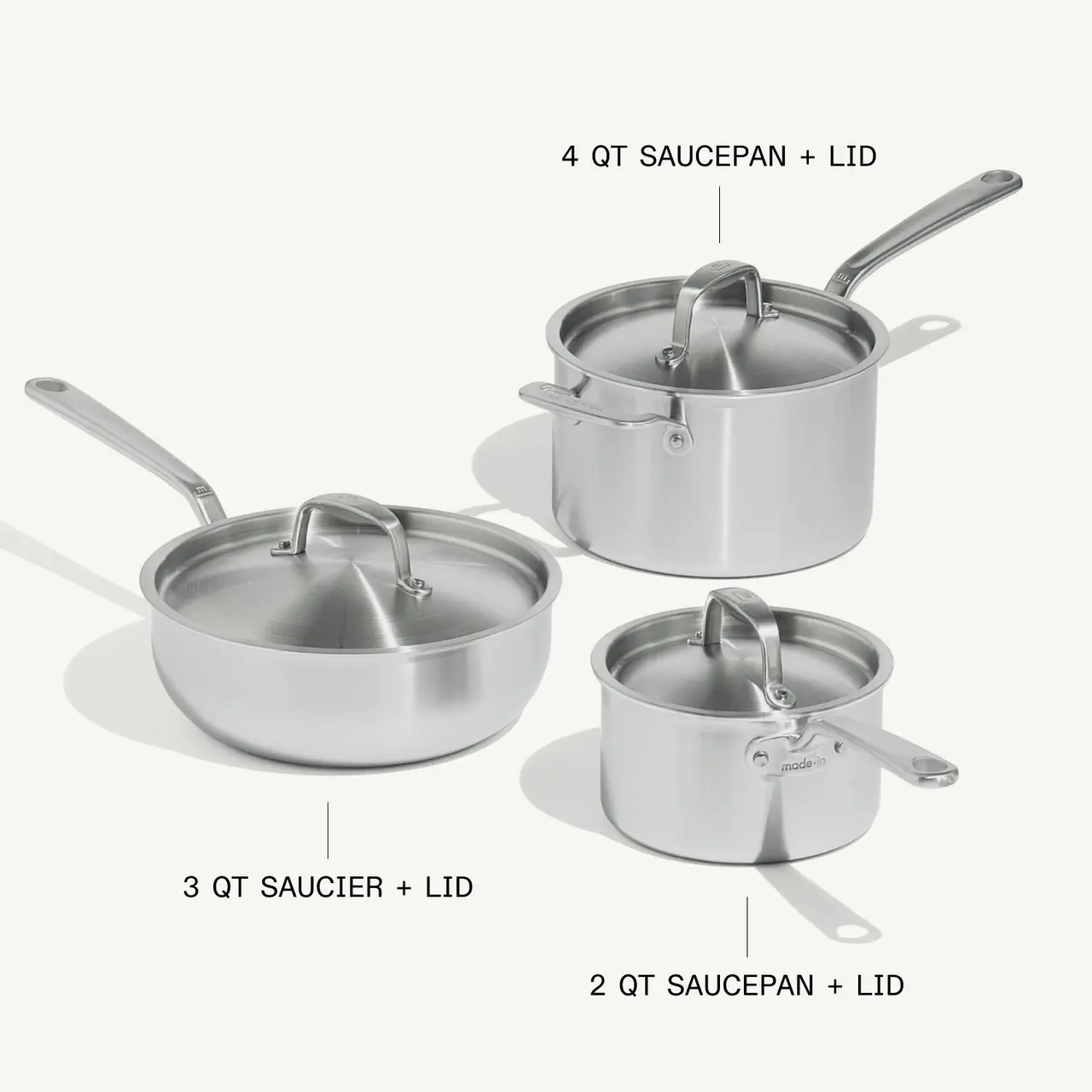 Three stainless steel cooking pots of varying sizes, including a 2-quart saucepan, a 3-quart saucier with a lid, and a 4-quart saucier with a lid, are displayed together.