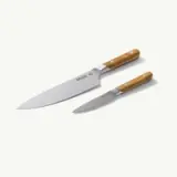 A chef's knife and a paring knife with wooden handles are displayed on a light background.