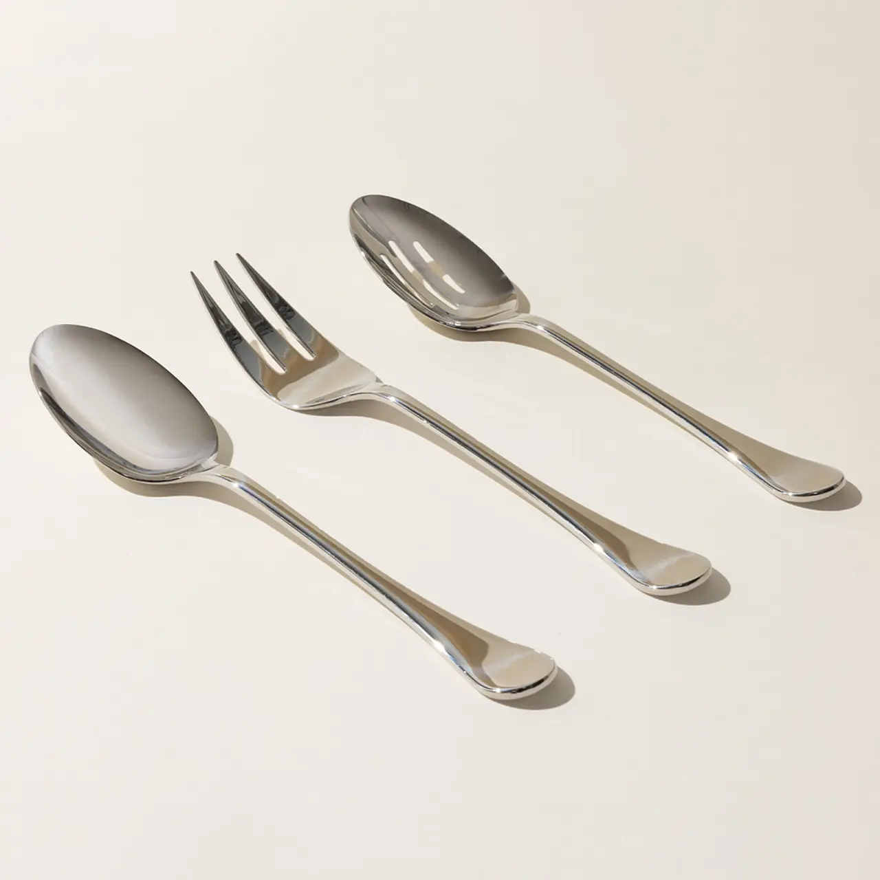 Two spoons and a fork are neatly arranged on a light background.