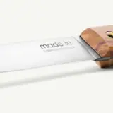 A close-up of a kitchen knife with a wooden handle and "made in France" engraved on the blade.