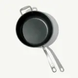 A round, non-stick frying pan with a stainless steel handle, casting a shadow on a light background.