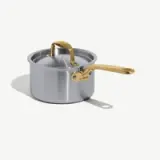 A stainless steel saucepan with a shiny gold handle and lid.