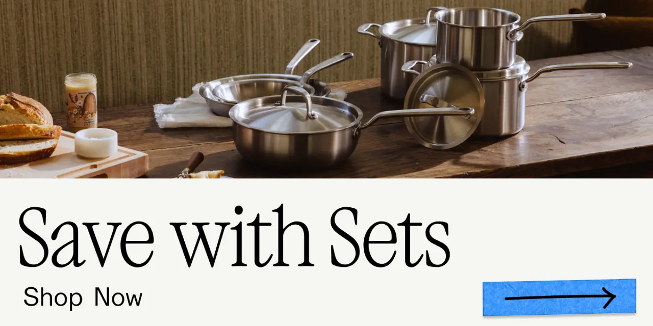 A collection of stainless steel cookware is displayed on a wooden surface, accompanied by text promoting savings on sets and a "Shop Now" button.