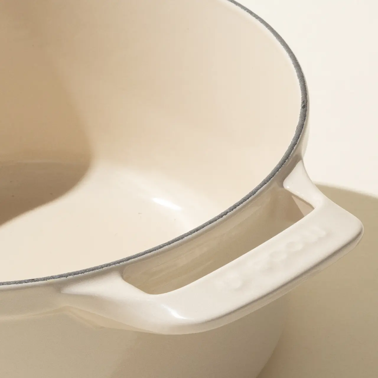 Close-up of a beige ceramic toilet with a grey toilet lid seal and a visible brand name on the ceramic.
