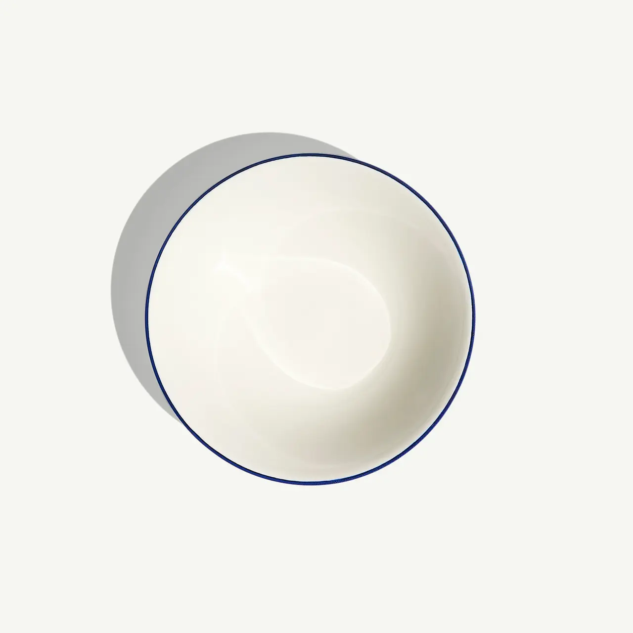 A white bowl with a thin blue rim on a light background.