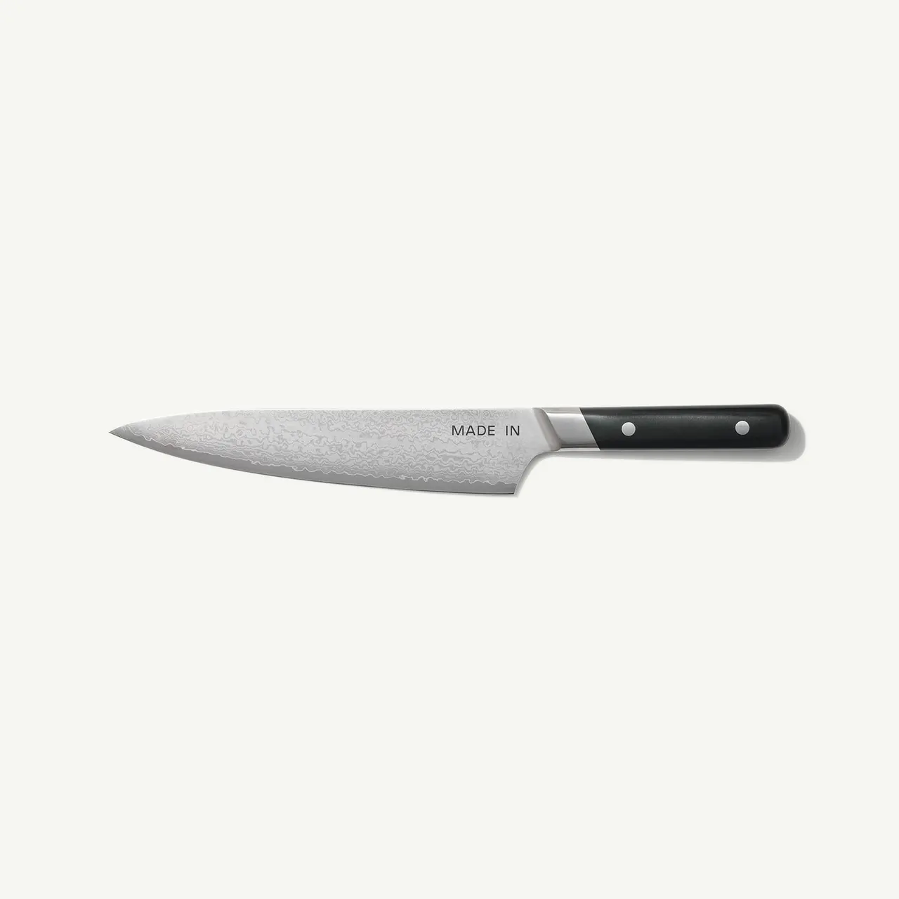 A stainless steel chef's knife with a black handle is placed against a plain white background.