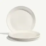 Four white ceramic plates are stacked together with one standing upright in the background.