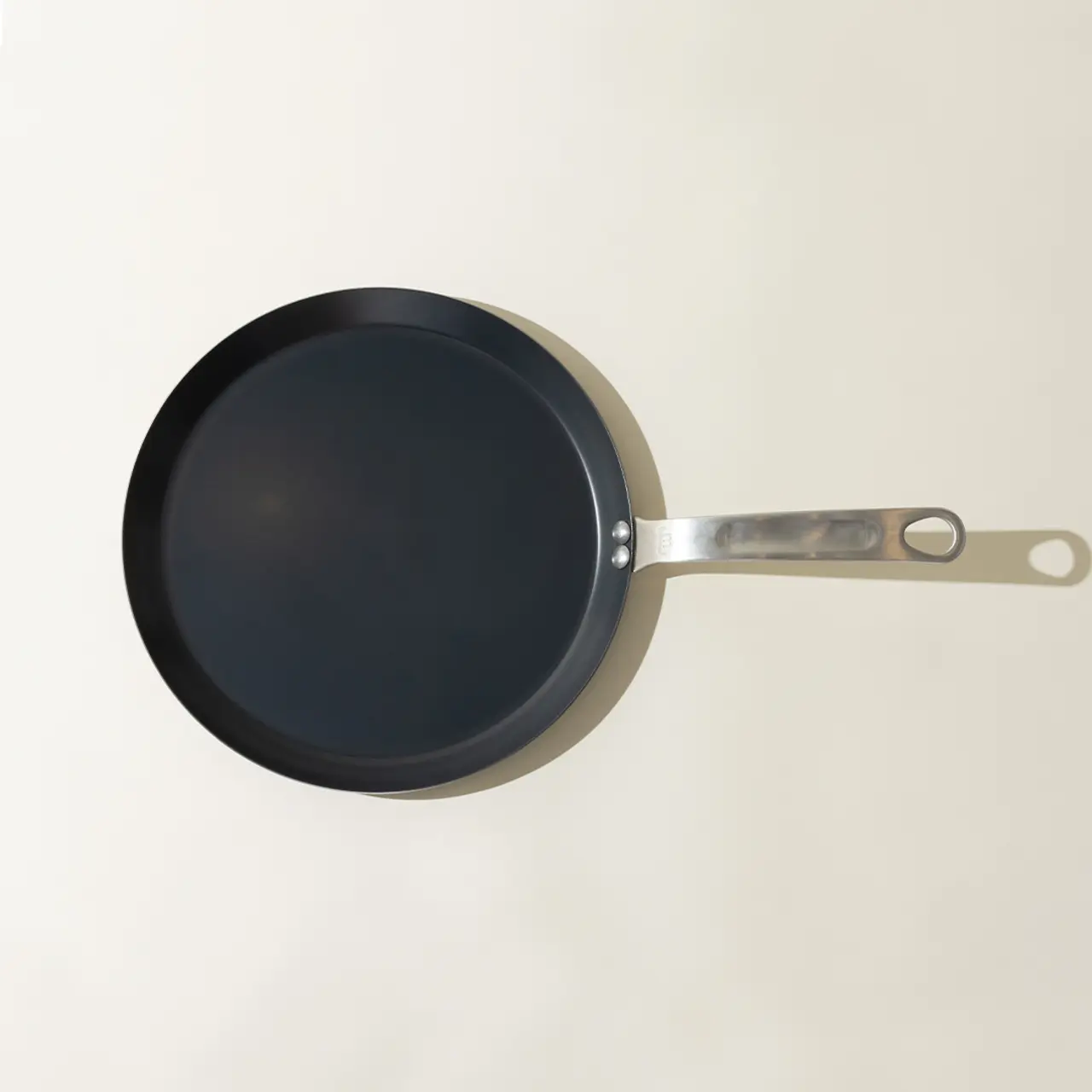 A new non-stick frying pan with a silver-colored handle placed against a neutral background.