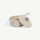 A beige cooking pot with a handle and a lid placed beside it.