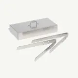 A rectangular stainless steel box with a handle on top and a pair of metal tongs are shown.