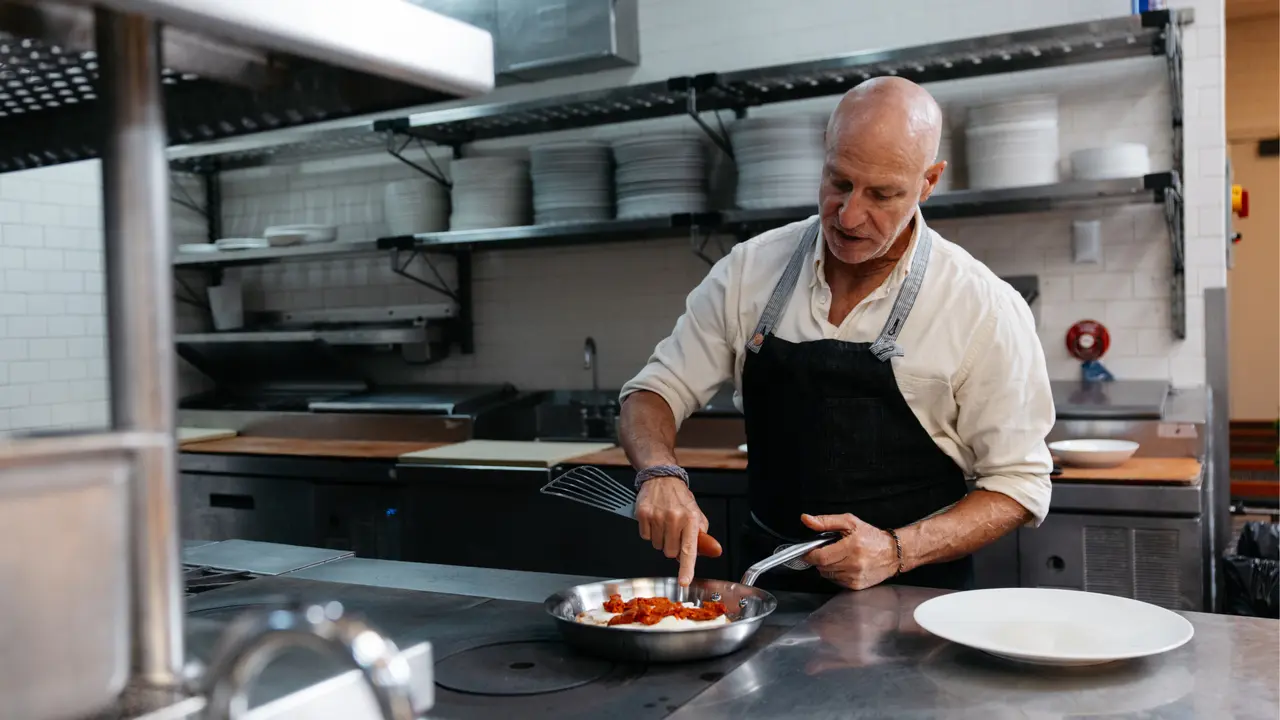 Chef Tom Colicchio cooks in a Made In stainless clad frying pan in a commercial kitchen.