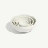 Four white ceramic bowls nested inside each other on a plain white background.