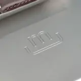 A metallic surface with a subtle "m" logo embossed in the center.