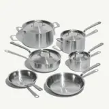 A six-piece set of stainless steel cookware including various pots, pans, and lids is arranged on a white background.