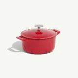 A red enameled cast iron Dutch oven with a lid and side handles is shown against a white background.